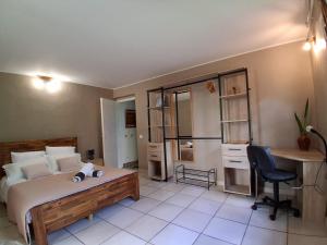 a bedroom with a bed and a desk and a chair at La Varangue in La Possession