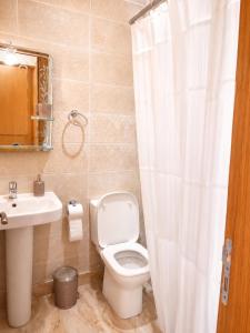 a bathroom with a white toilet and a sink at Perla Andalusia Bright 2BR Near Beach & Pool in Mansouria +3 photos