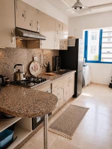 a kitchen with a granite counter top and a refrigerator at Perla Andalusia Bright 2BR Near Beach & Pool in Mansouria