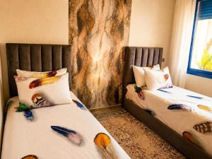 a bedroom with two beds with feathers on the sheets at Perla Andalusia Bright 2BR Near Beach & Pool in Mansouria