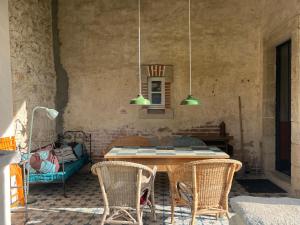 eine Terrasse mit Tisch, Stühlen und zwei Lampen in der Unterkunft L'école perdue in Saint-Martin-dʼOllières
