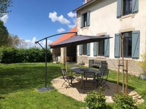 ein Tisch und Stühle unter einem Sonnenschirm im Garten in der Unterkunft L'école perdue in Saint-Martin-dʼOllières