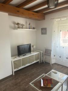 a living room with a flat screen tv and a table at El Descanso Lastres in Colunga