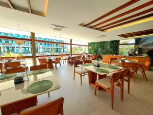 a restaurant with tables and chairs and windows at Resort Mana Beach Experience By Beachflatsporto in Porto De Galinhas