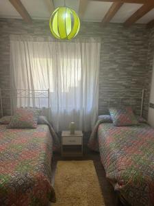 a bedroom with two beds and a chandelier at El Descanso Lastres in Colunga