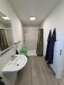 a bathroom with a white sink and a shower at Timmendorfer Herz in Timmendorfer Strand +39 photos
