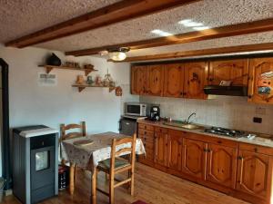 a kitchen with wooden cabinets and a table and a stove at Nido Paradiso Nido, Balcone panoramico sulla Valle Soana in Ingria