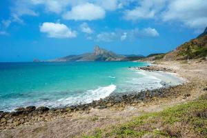 a beach with a mountain in the background at Le Condor House and Café in Con Dao