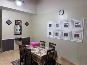 a dining room with a table and a clock on the wall at Labis Homestay Afina in Labis