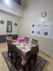 a dining room with a table with chairs and a clock on the wall at Labis Homestay Afina in Labis
