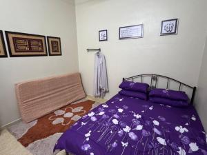 a bedroom with a bed with a purple comforter at Labis Homestay Afina in Labis