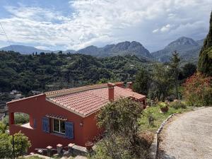 a red house on a hill with mountains in the background at Studio Shangri-LA - Entrée & terrasse privatives - Vue mer - Parking in Menton