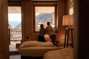 two people sitting on beds in a room looking out the window at Hotel Masl in Valles