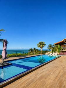 a swimming pool with the ocean in the background at Pousada Hope Club in Beberibe