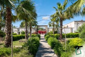 a path through a garden with palm trees at Hotiday Torre Guaceto in Brindisi