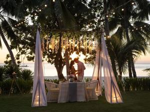 a couple standing at a table in front of the ocean at Movenpick Resort & Spa Boracay in Boracay +161 photos