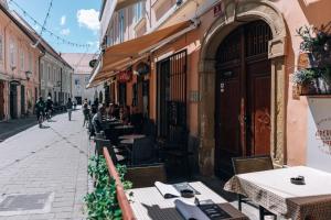 an empty street with tables and people sitting outside a restaurant at 4 Rooms in Maribor