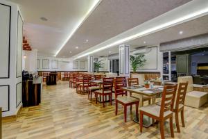 a restaurant with tables and chairs and a kitchen at Banari Regency by Summit in Namchi