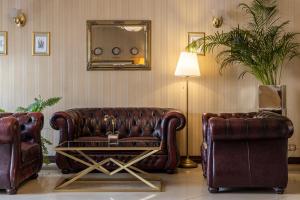 a living room with a leather couch and two chairs at Gertrude Hotel self check-in in Riga