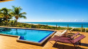 a swimming pool with two chairs and the beach at Pousada Hope Club in Beberibe