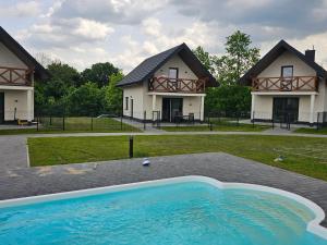 a large swimming pool in front of a house at Mazurska Osada in Januszkowo +12 photos
