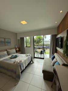 a bedroom with a bed and a couch and a patio at Resort Mana Beach Experience By Beachflatsporto in Porto De Galinhas +107 photos