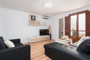 a living room with a black couch and a tv at Can M Tatau in Santanyi