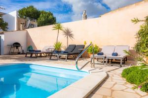 a patio with a swimming pool and chairs and a house at Can M Tatau in Santanyi