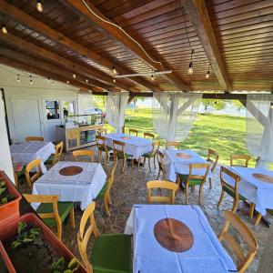 a restaurant with white tables and chairs at BORA- Popas Turistic casute de vacanta in Fîrdea