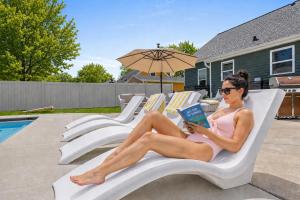 a woman sitting on a lounge chair reading a book at Lambeau View Pool Rooftop Entertainment Room in Green Bay