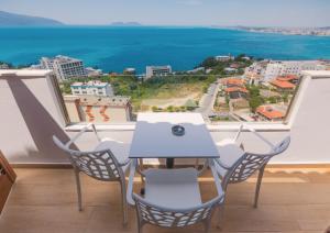 a table and chairs on a balcony with a view of the ocean at Vila Dena in Vlorë