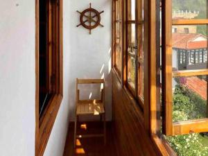 a room with a window with a chair and a clock at La casina de La Fragua in Lastres