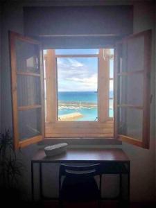 a window with a view of the ocean from a desk at La casina de La Fragua in Lastres