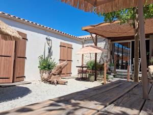 a patio with a table and an umbrella at Chambres D'hôtes La Marouette in Hiers-Brouage