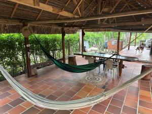 a hammock on a patio with a table and chairs at El descanso del sol llanero in San Luis de Palenque