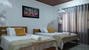 a bedroom with two beds and a window at El descanso del sol llanero in San Luis de Palenque