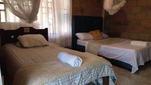 a bedroom with two beds and a brick wall at El descanso del sol llanero in San Luis de Palenque +5 photos