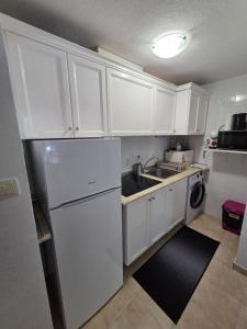 a kitchen with white cabinets and a white refrigerator at Appartement calme et confort in La Florida