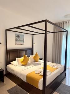 a bedroom with a canopy bed with yellow pillows at Lion Gate Hotel Sigiriya in Sigiriya