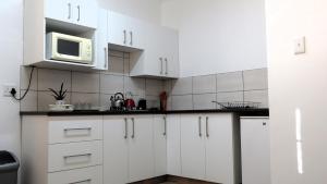 Eine weiße Küche mit weißen Schränken und einer Mikrowelle in der Unterkunft Die Regte Plek in Despatch + 10 Fotos