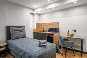 a bedroom with a bed and a desk and a kitchen at Central Platinum Apartments 10 in Rybnik