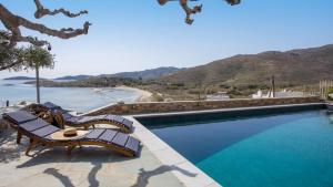 a swimming pool with two benches next to a beach at Astraea Villa in Karistos