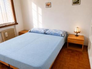 a bedroom with a blue bed and a night stand at Charming House Among the Prosecco Hills & Olive Groves in San Pietro di Feletto