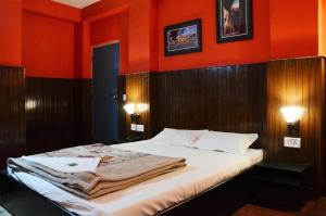 a bedroom with a bed with red walls at Hotel Kalika Darjeeling in Darjeeling
