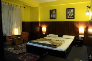 a bedroom with a bed and a yellow wall at Hotel Kalika Darjeeling in Darjeeling