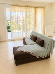 a couch in a living room with a large window at Treasure B&B - Garden Stay in Paloukia Salamina in Paloúkia