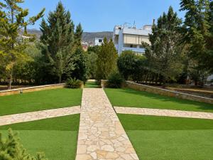 a garden with green grass and a pathway at Treasure B&B - Garden Stay in Paloukia Salamina in Paloúkia