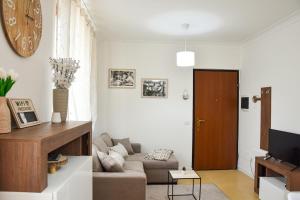 a living room with a couch and a clock on the wall at 10 min from the lake, Spacious & Modern - Lalaland in Porto Ceresio