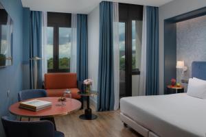 a hotel room with a bed and a chair and a table at NH Firenze in Florence