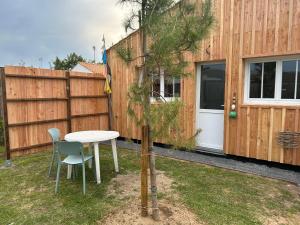 a table and chairs and a pine tree in a yard at Sam Va in Dolus-d'Oléron